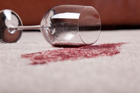 Red wine spill on white carpet from wine glass